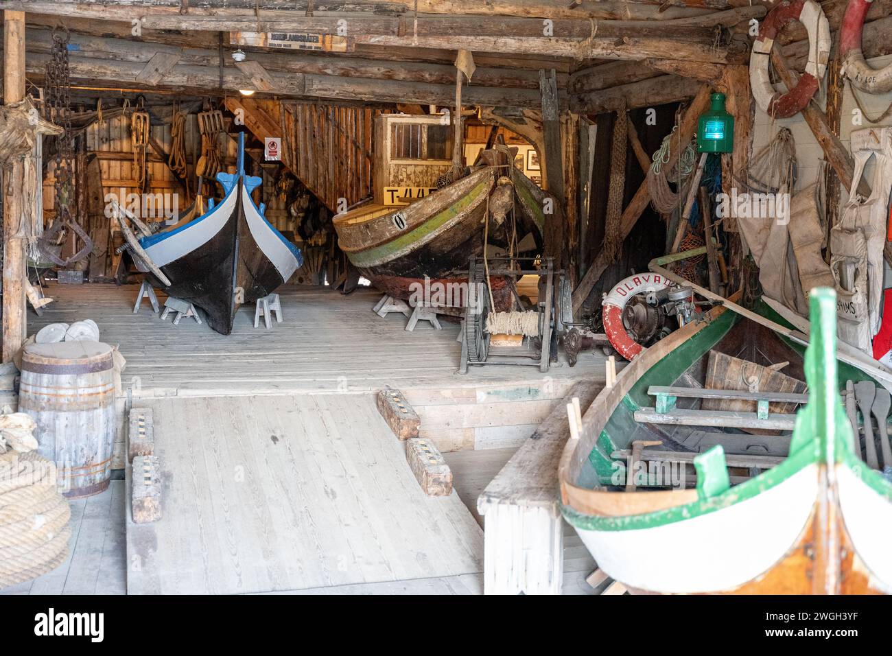 Una collezione di barche ben conservate su pilastri di legno all'interno di un garage Foto Stock