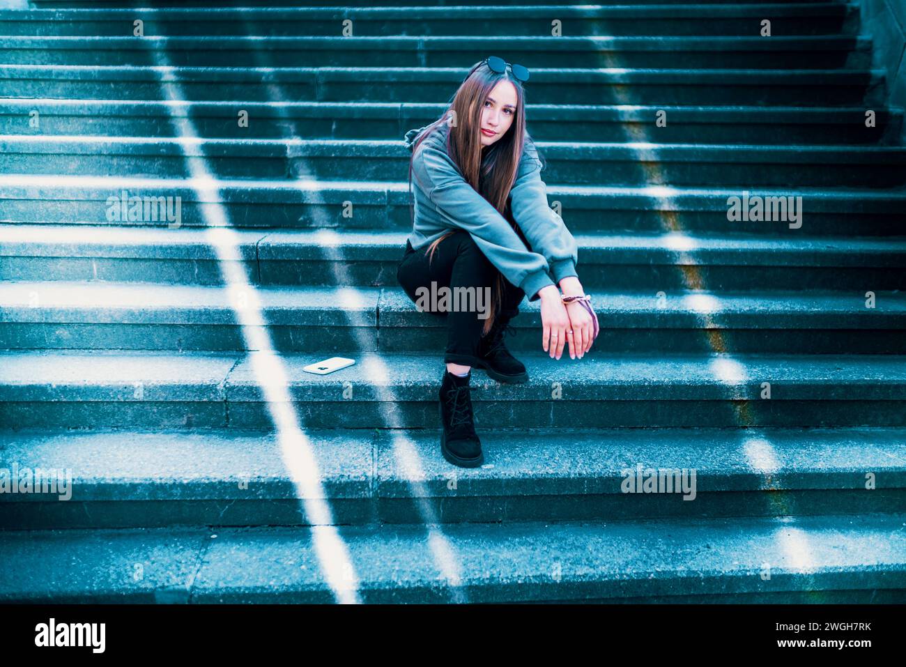 giovane donna che posa seduta su gradini di lastra di pietra Foto Stock