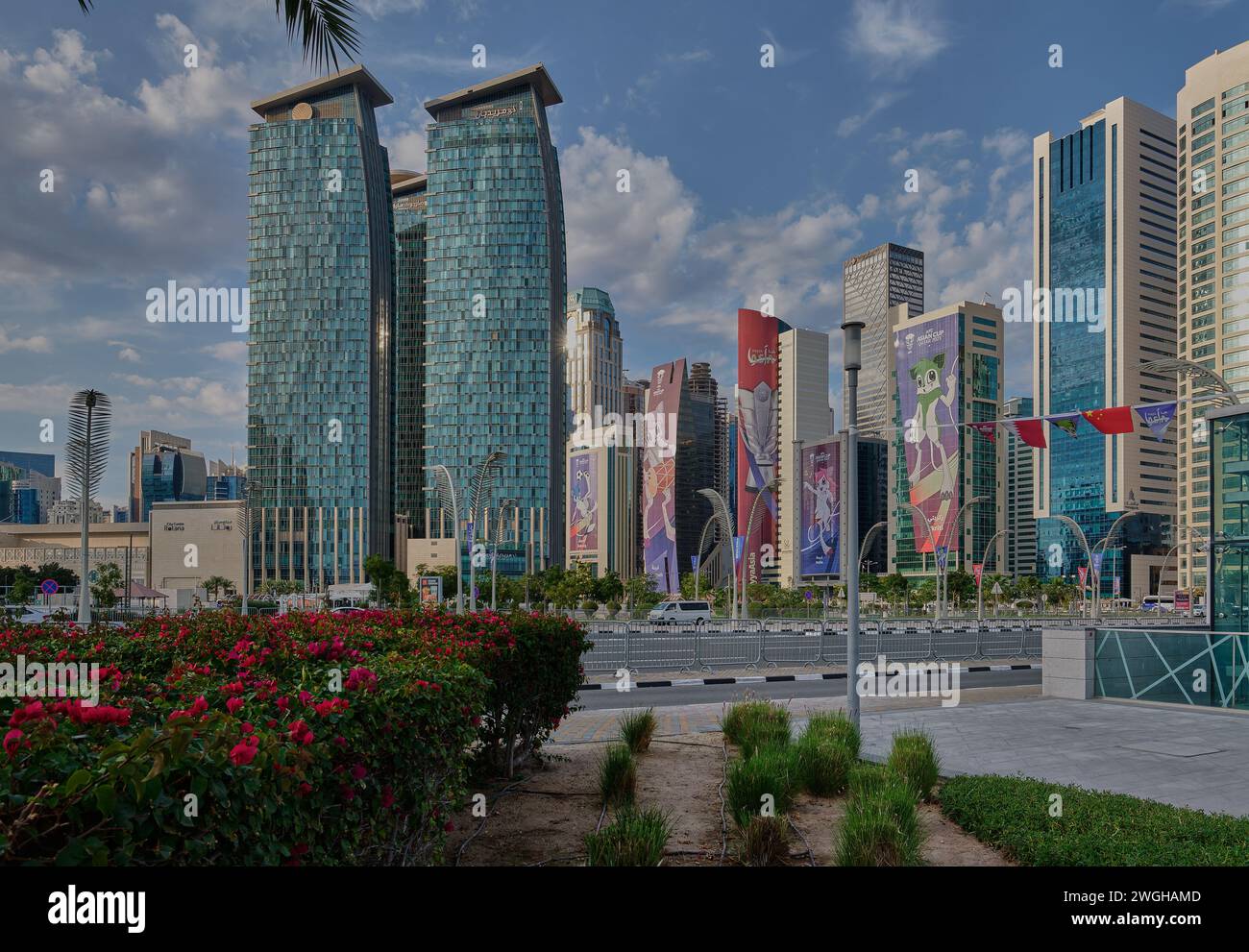 Skyline di Doha nel quartiere della West Bay Doha, vista del tramonto in Qatar con le mascotte della Coppa d'Asia 2023 dell'AFC sugli edifici e le nuvole nel cielo Foto Stock