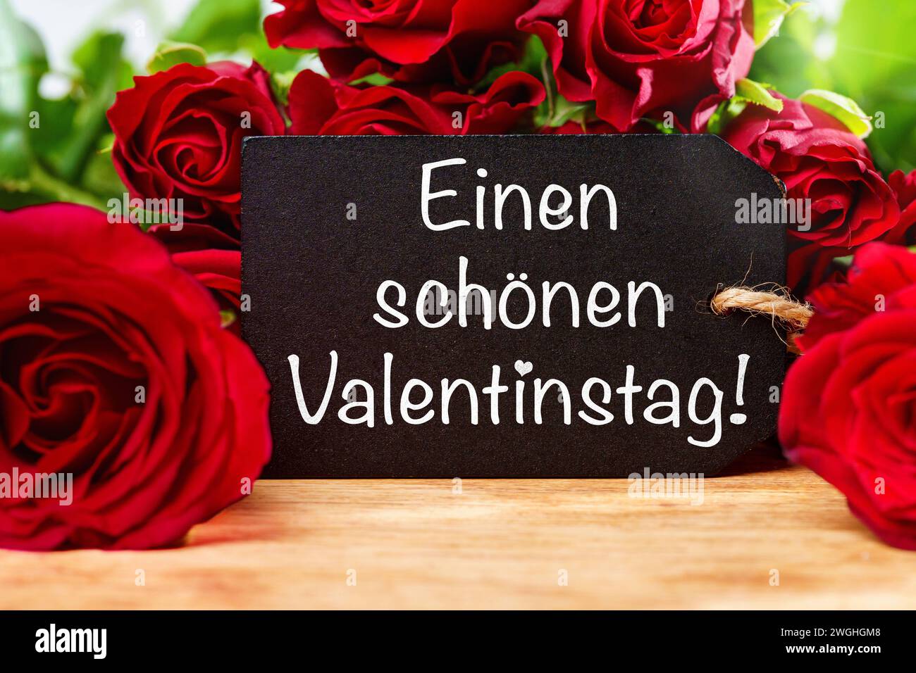5 febbraio 2024: Saluto di San Valentino su un cartello di fronte alle rose rosse FOTOMONTAGE *** einen schönen Valentinstag Gruß auf einem Schild vor roten Rosen FOTOMONTAGE Foto Stock