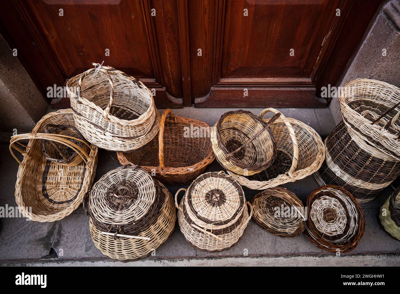 Ci sono tantissimi cesti di vimini intrecciati per terra. Foto Stock