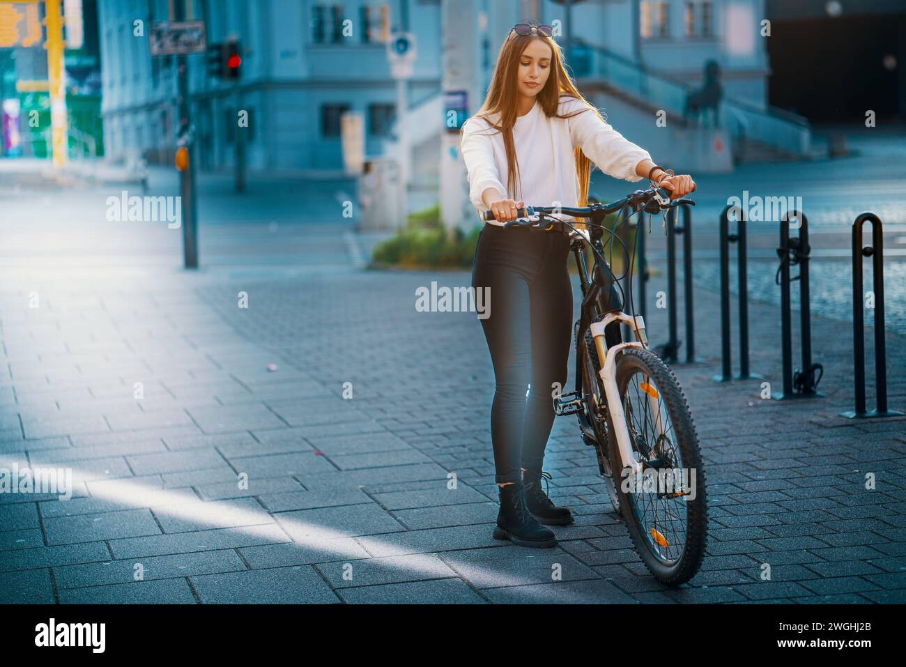 Giovane donna in bicicletta per le strade della città con un sorriso Foto Stock