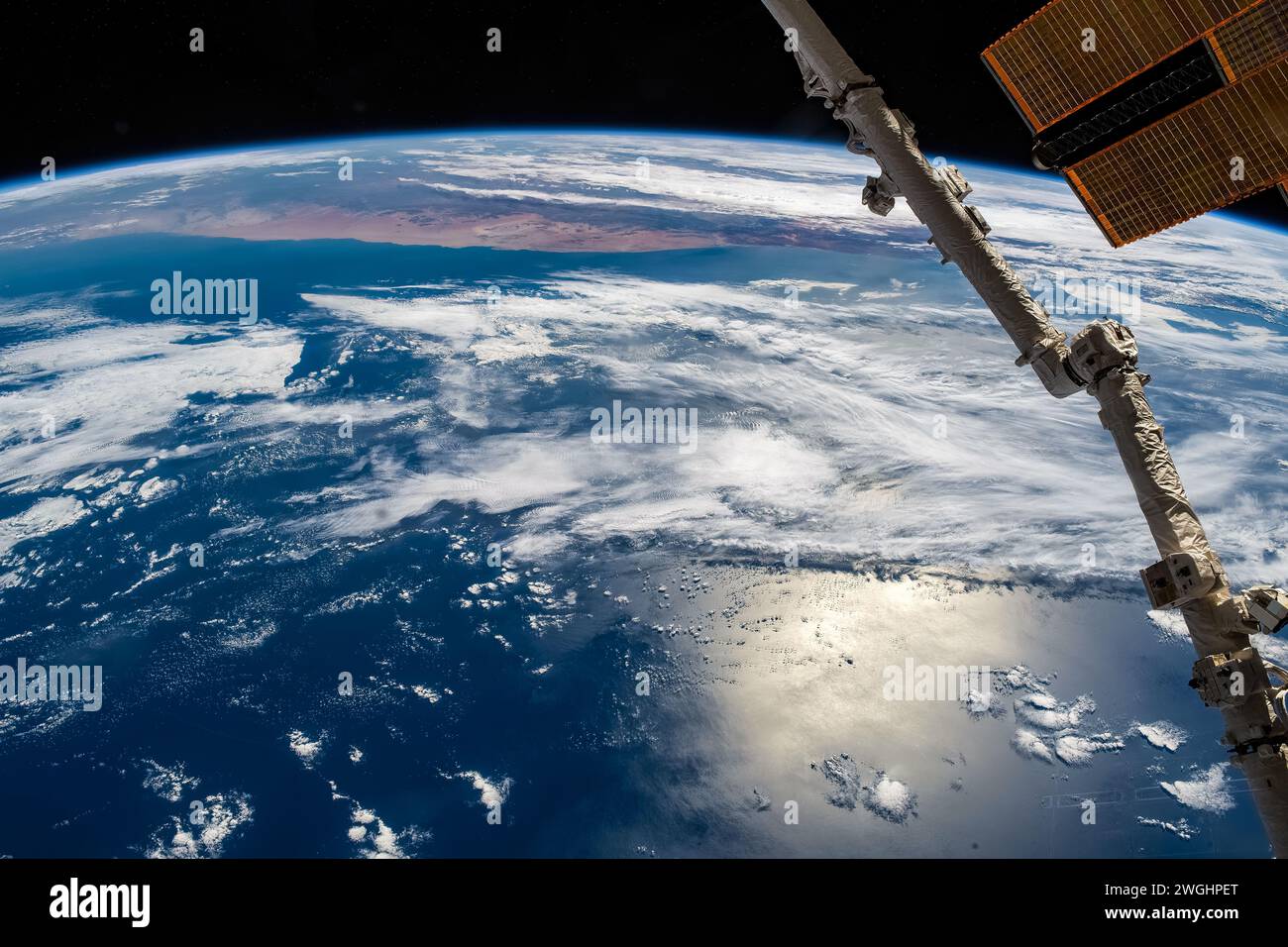 Fusoliera Canadarm ISS, riflesso della luce solare nell'acqua di mare, l'orizzonte del pianeta Terra Foto Stock