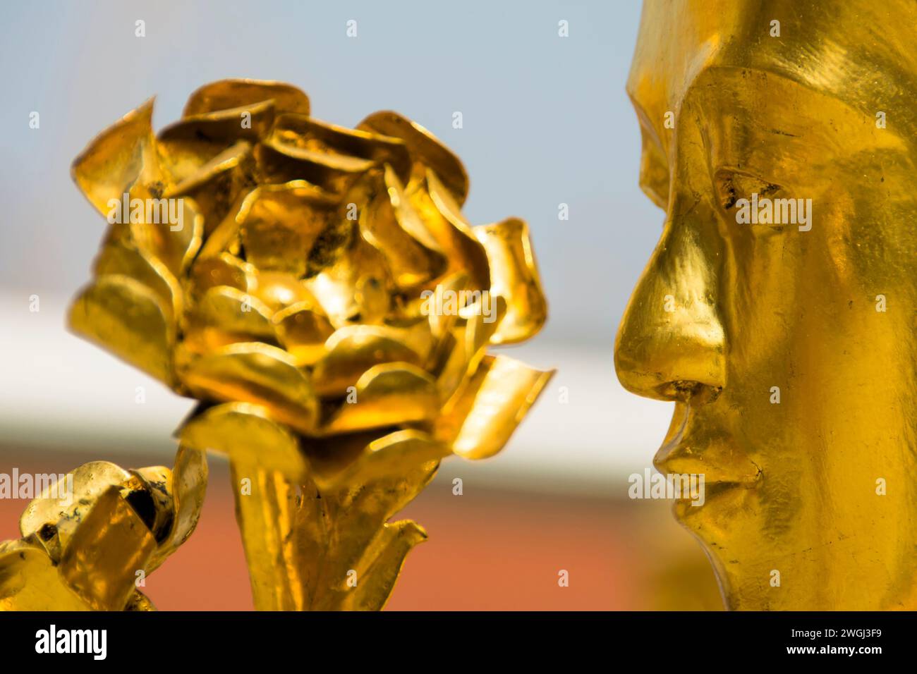 Fiore d'oro che adorna una maestosa statua con il volto di un uomo Foto Stock