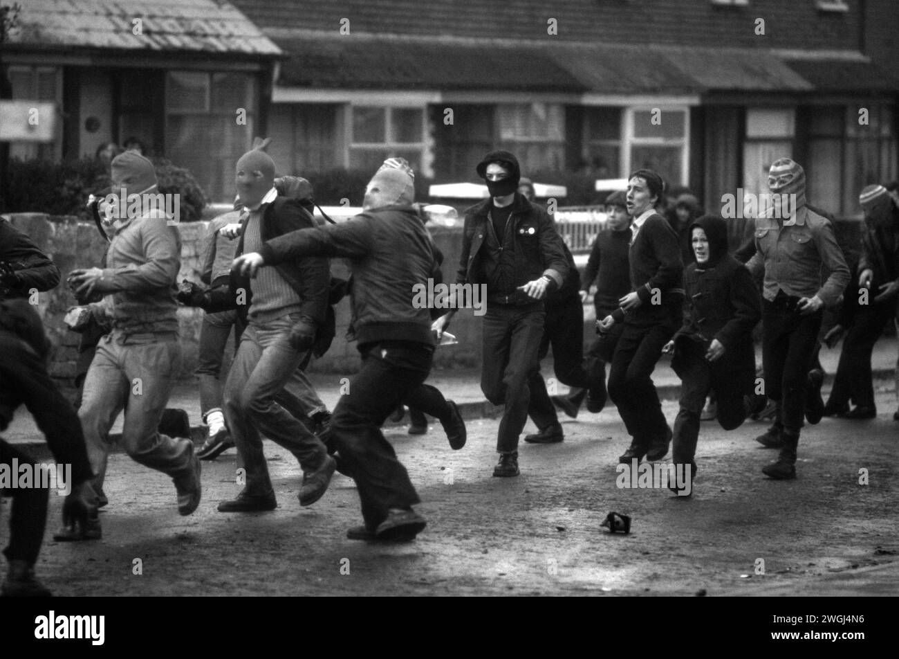 Belfast, Irlanda del Nord, circa maggio 1981. I problemi che caricano la rivolta cattolica i giovani travestiti da balaclava lanciano bombe a benzina contro l'esercito britannico a Etna Drive, Ardoyne a nord di Belfast. Foto Stock