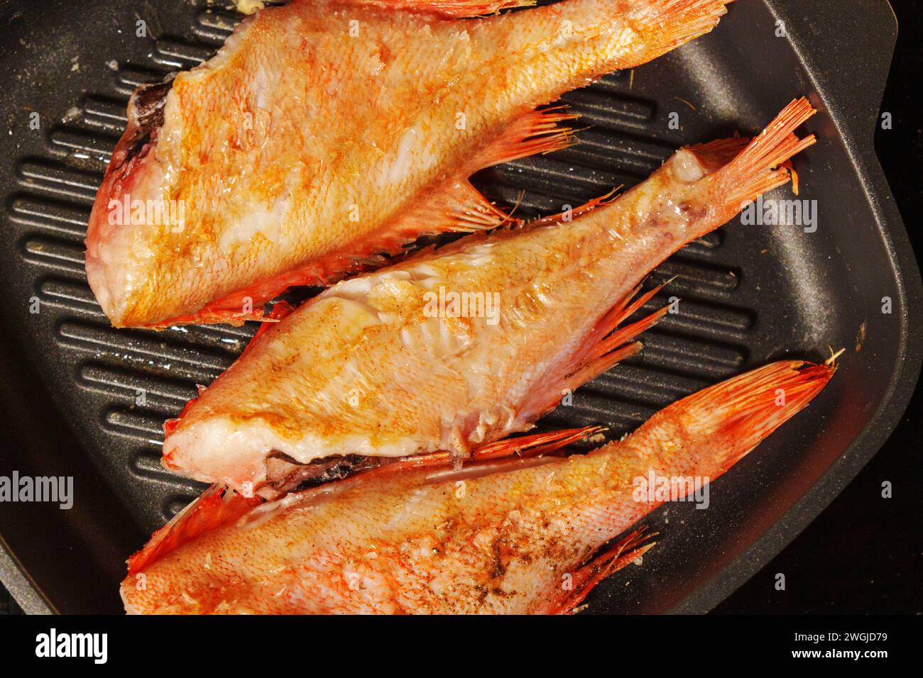 Branzino che si sprigiona mentre grigliano alla perfezione in un ambiente caldo. Foto Stock