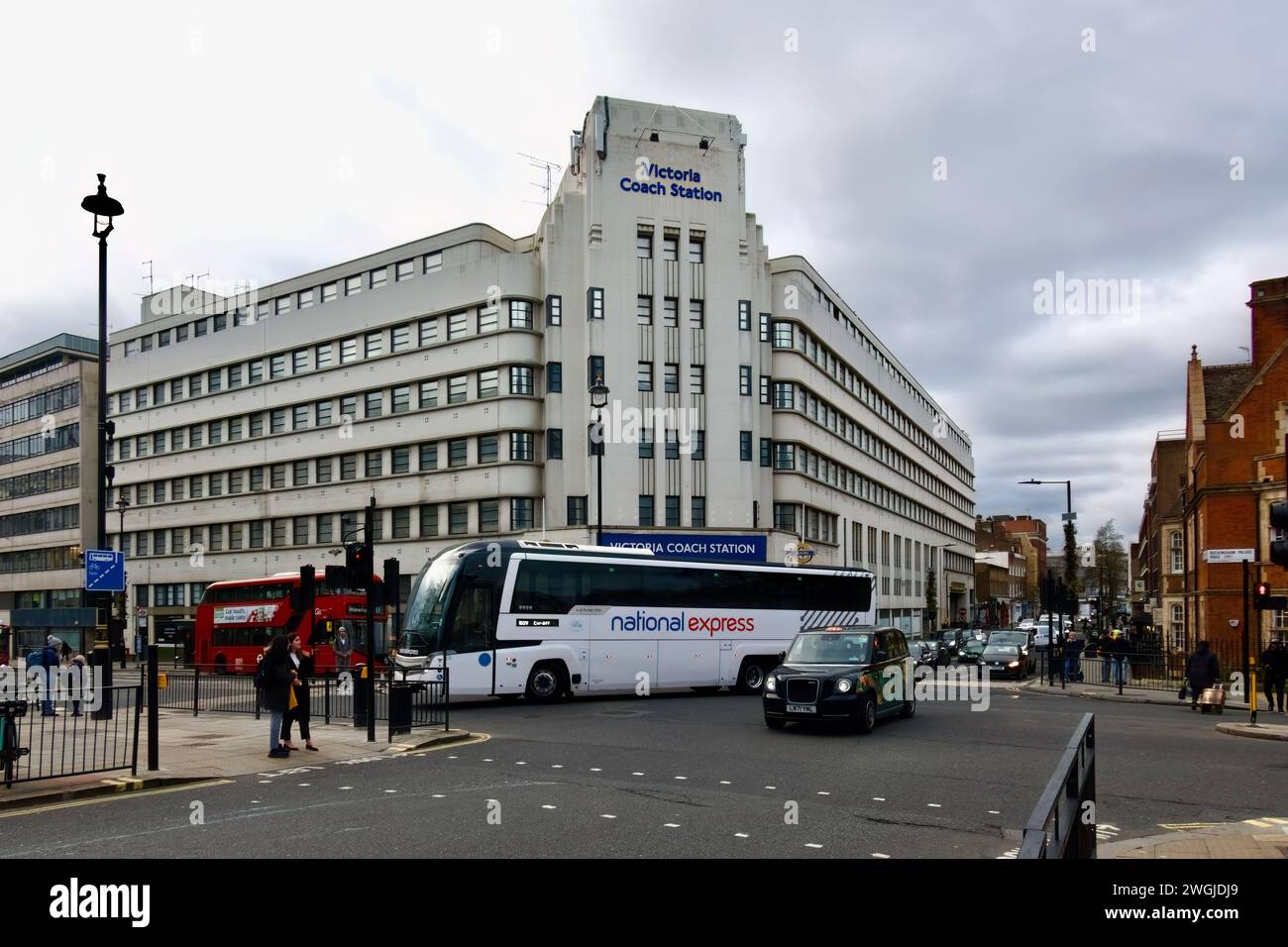 Un autobus National Express che gira di fronte alla stazione degli autobus Victoria con un taxi nero e un autobus rosso da Elizabeth Bridge Londra Inghilterra Regno Unito Foto Stock