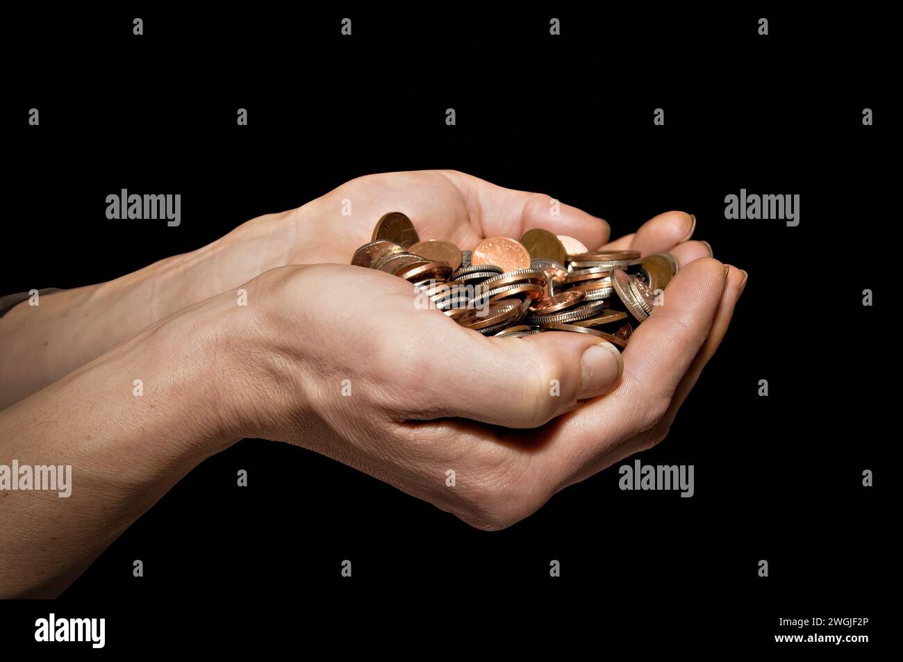 Maschio caucasico (42 anni) con le mani tenute fuori piene di soldi su uno sfondo nero Foto Stock
