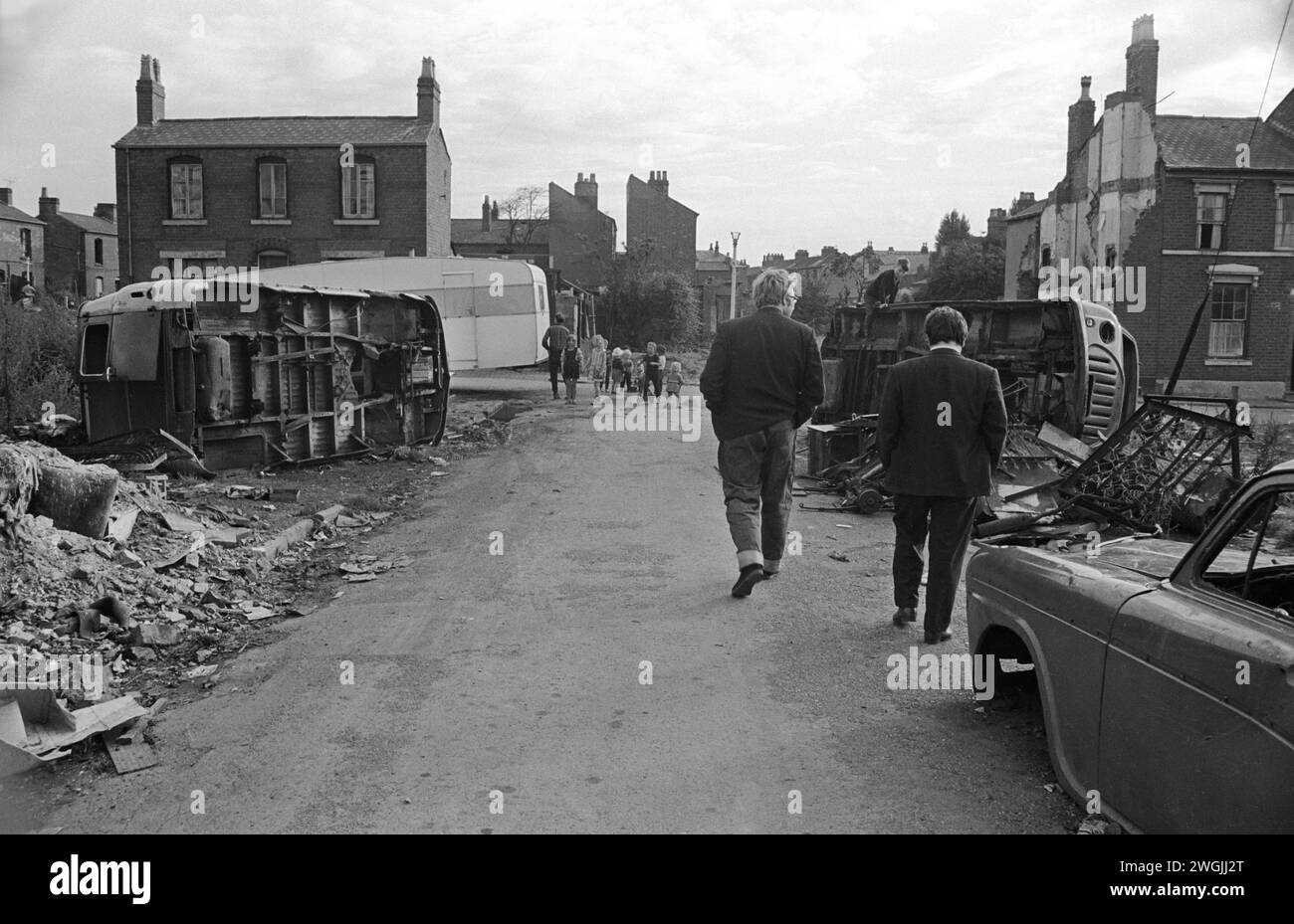 Un accampamento di viaggiatori irlandesi zingari e un deposito temporaneo di rottami di auto sul terreno di rifiuti a Balsall Heath, nel Regno Unito degli anni '1960. Balsall Heath era un'area urbana. La strada verso cui gli zingari stanno camminando è Wenman Street. Queste macchinette si guadagnavano da vivere raccogliendo rottami di metallo, quindi lo scarico dell'auto. Il campo è dove si trovano Gosforth e Knutsford Street. Balsall Heath, Birmingham, Inghilterra marzo 1968. HOMER SYKES Foto Stock
