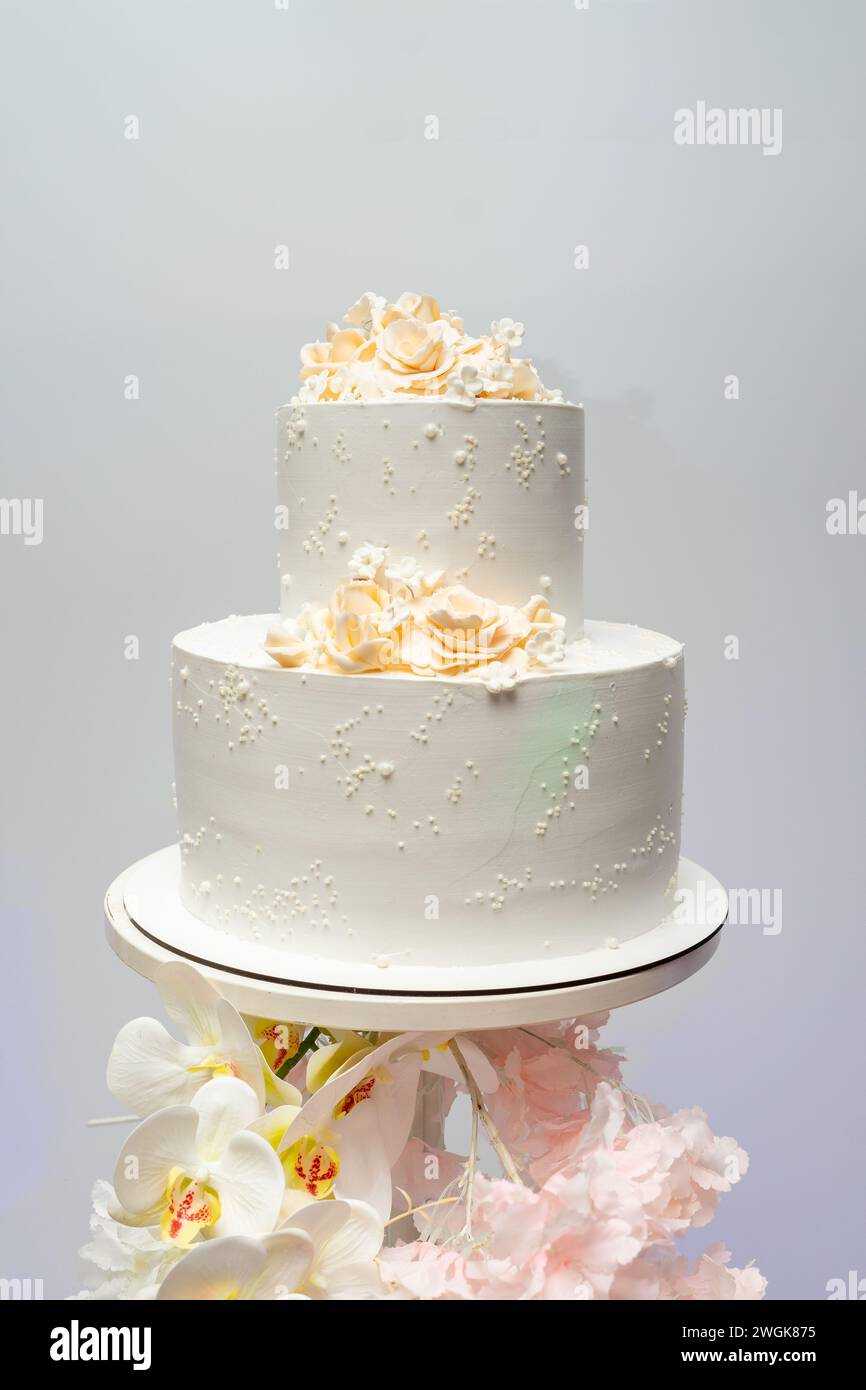 Torta nuziale bianca a due piani decorata con fiori. Foto Stock