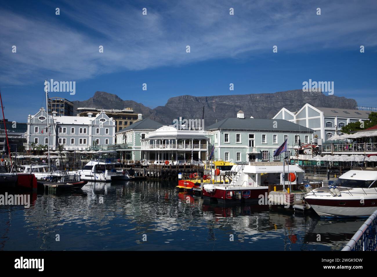 Table Mountain dietro le barche e gli edifici sul lungomare V&A sotto il cielo blu a Capetown, Sudafrica Foto Stock