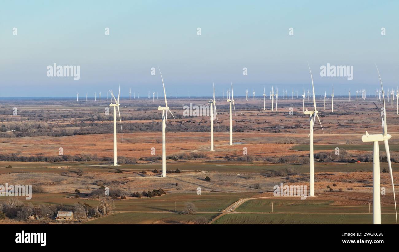 Alcune turbine eoliche in un campo pittoresco durante il tramonto, situate vicino a una strada rustica e a un terreno agricolo Foto Stock