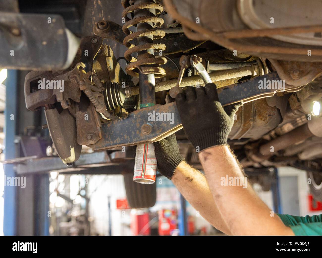 Meccanico di auto che lavora in officina di riparazione auto. Uomo in uniforme che lavora con il motore dell'auto. Foto Stock