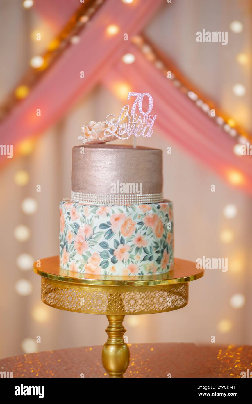 Torta di compleanno per festeggiare i settant'anni, fiori semplici e piccanti da vicino, splendido sfondo illuminato con calore Foto Stock