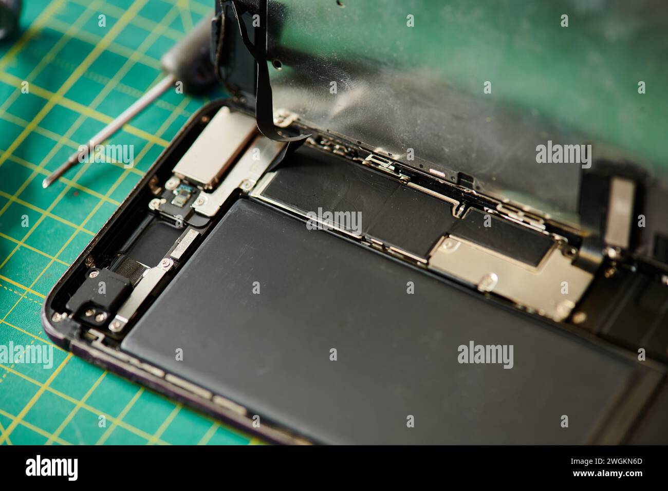 telefono cellulare e cacciavite rotti sul tavolo dell'officina di riparazione, concetto aziendale di riparazione elettronica Foto Stock