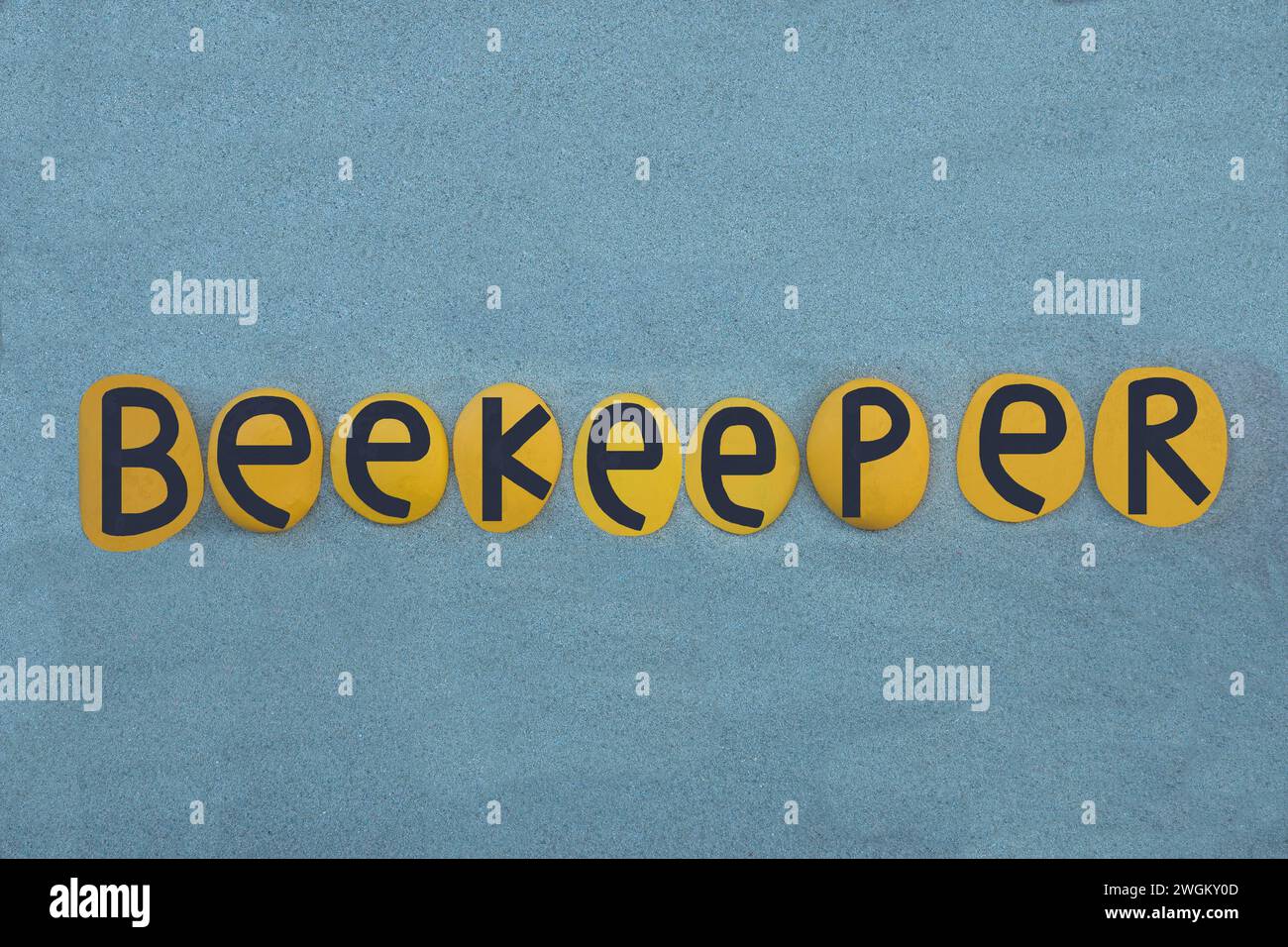 Apicoltore, una persona che tiene api mellifere, una professione nota come apicoltura, testo creativo composto da lettere gialle e nere su sabbia verde Foto Stock