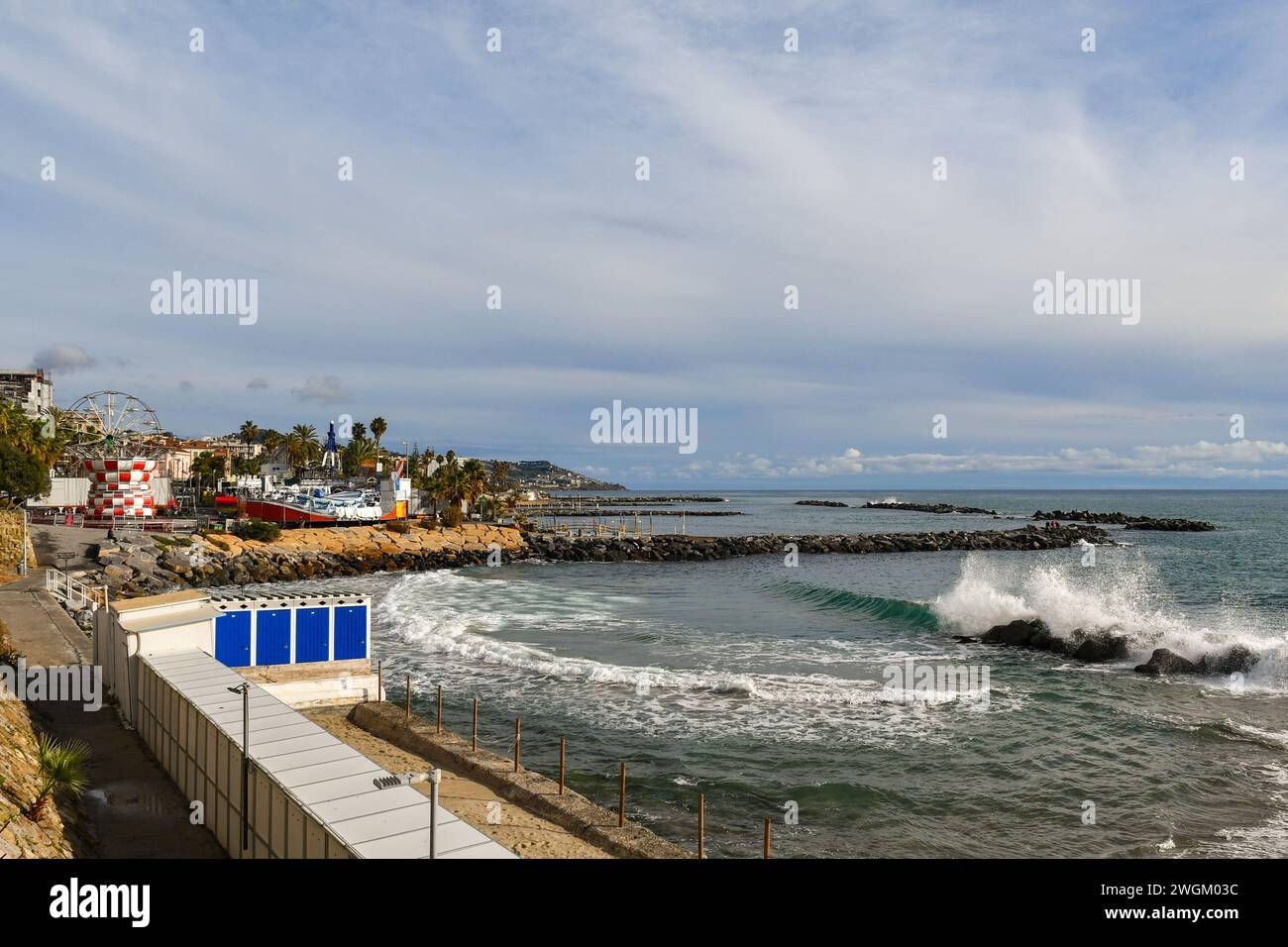 Vista sopraelevata del lungomare con alte onde che si infrangono sulla spiaggia e il Luna Park con la ruota panoramica in inverno, Sanremo, Liguria, Italia Foto Stock