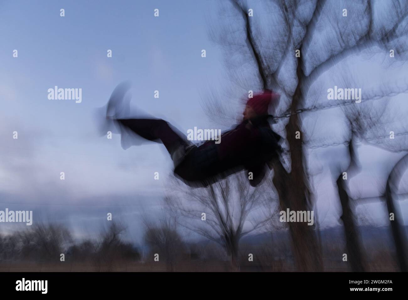 immagine di una donna su un'altalena al crepuscolo con movimento sfocato Foto Stock