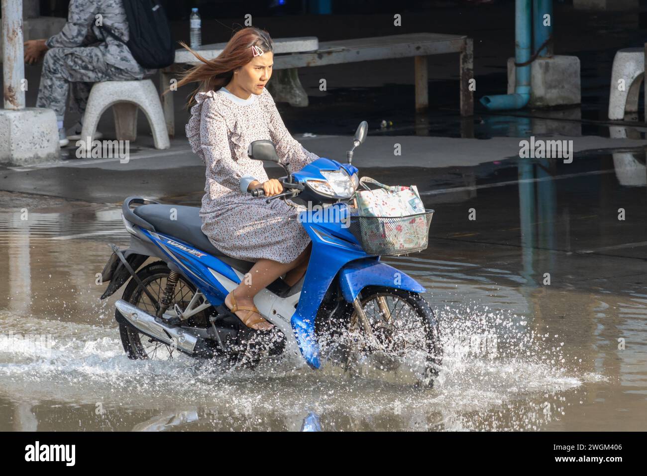 SAMUT PRAKAN, THAILANDIA, novembre 28 2023, Una donna in moto guida attraverso una strada allagata Foto Stock