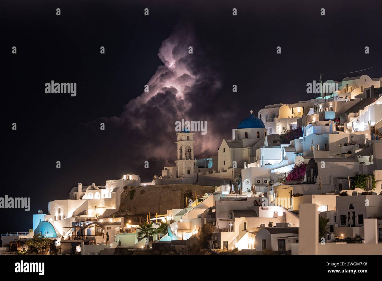 Illuminare il divino: Un accattivante fulmine su una chiesa nell'incantevole Santorini, Grecia. Foto Stock