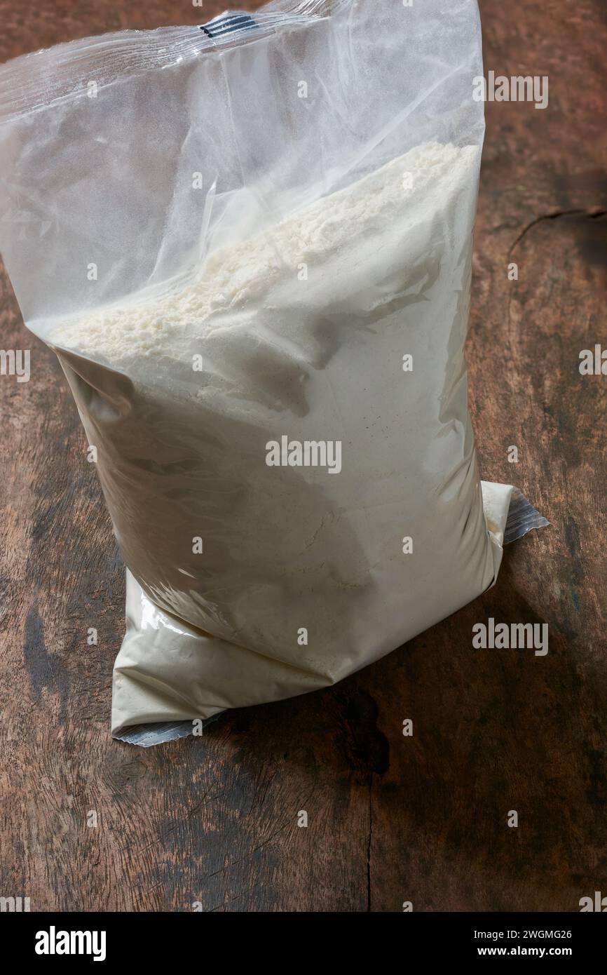 sacchetto di farina in plastica trasparente, posto su un tavolo in legno rustico o su sfondo superficiale, modello di mockup confezione vuota dell'ingrediente per la cottura Foto Stock