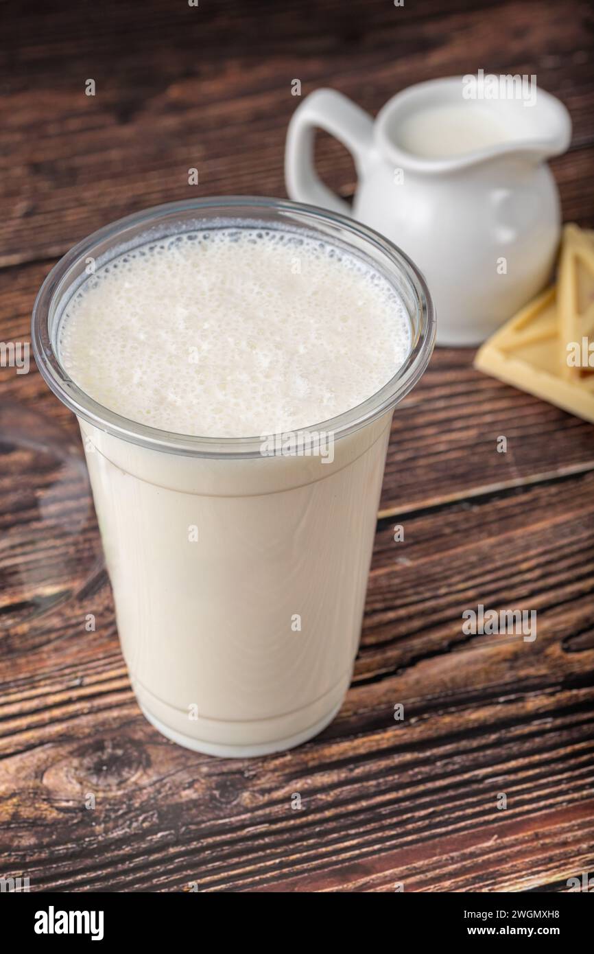 Latte di cioccolato bianco in vetro da asporto su un tavolo di legno Foto Stock