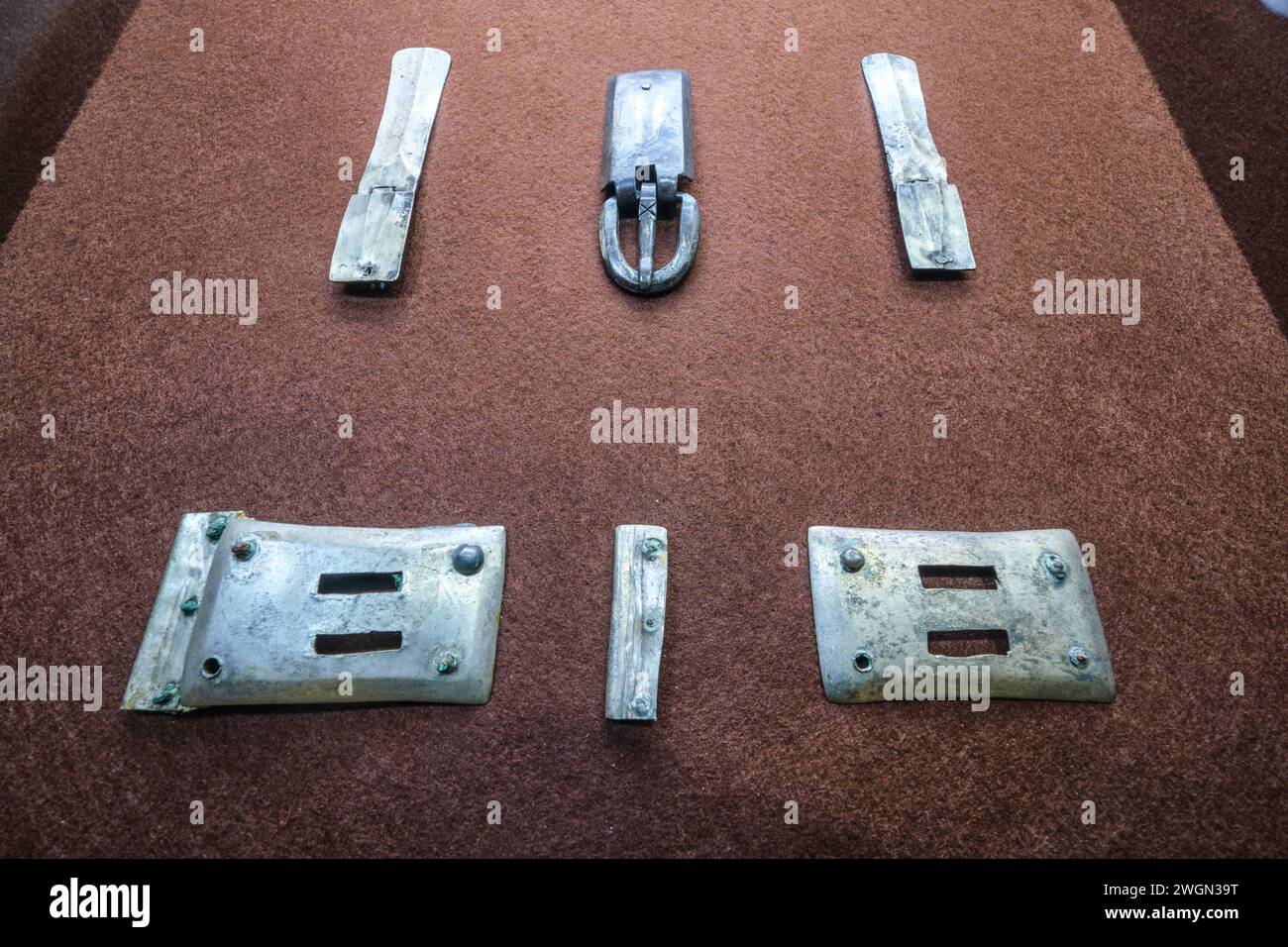 Una collezione di semplici fibbie e ganci per cintura in metallo color argento, stampati. Al Museo Archeologico di Almaty, Kazakistan. Foto Stock