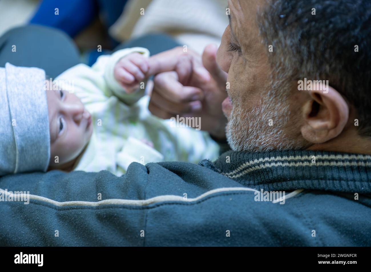 Nonno che tiene in braccio il bambino con un sorriso sul viso, barba grigia, bimbo che tiene il dito Foto Stock