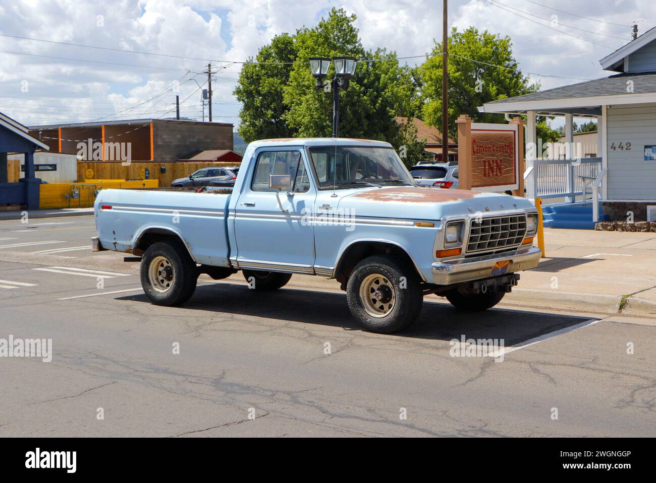 Un pick-up blu d'epoca parcheggiato sulla strada in una piccola città con edifici circostanti e cieli limpidi. Foto Stock