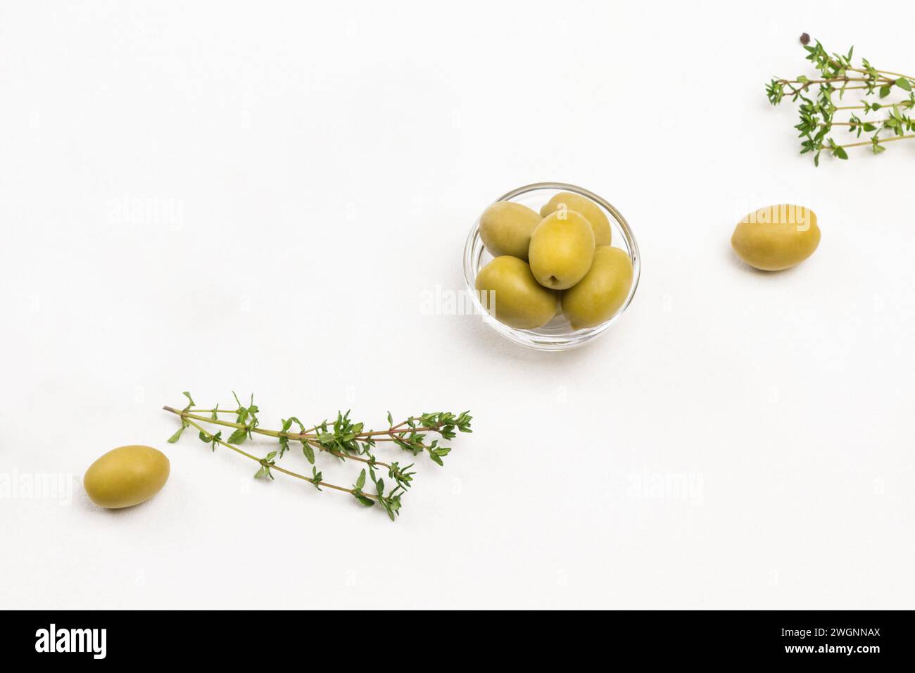 Olive verdi e ciuffi di timo su sfondo bianco. Copia spazio. Sfondo bianco. Posizione piatta. Foto Stock