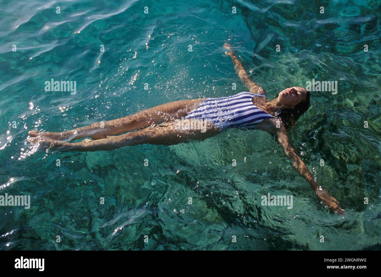 bella ragazza dai capelli scuri stendendosi sul prosciutto d'acqua di mare che galleggia sulle vacanze estive mare sullo sfondo Foto Stock