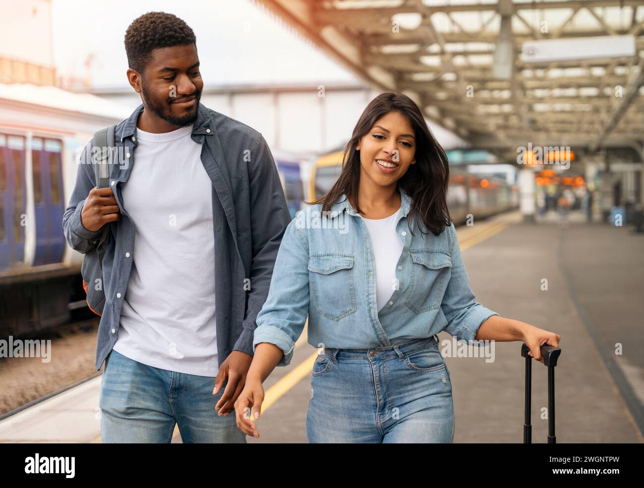 giovane coppia di famiglie che cammina lungo la piattaforma ferroviaria per prendere il treno per andare in vacanza, in vacanza Foto Stock
