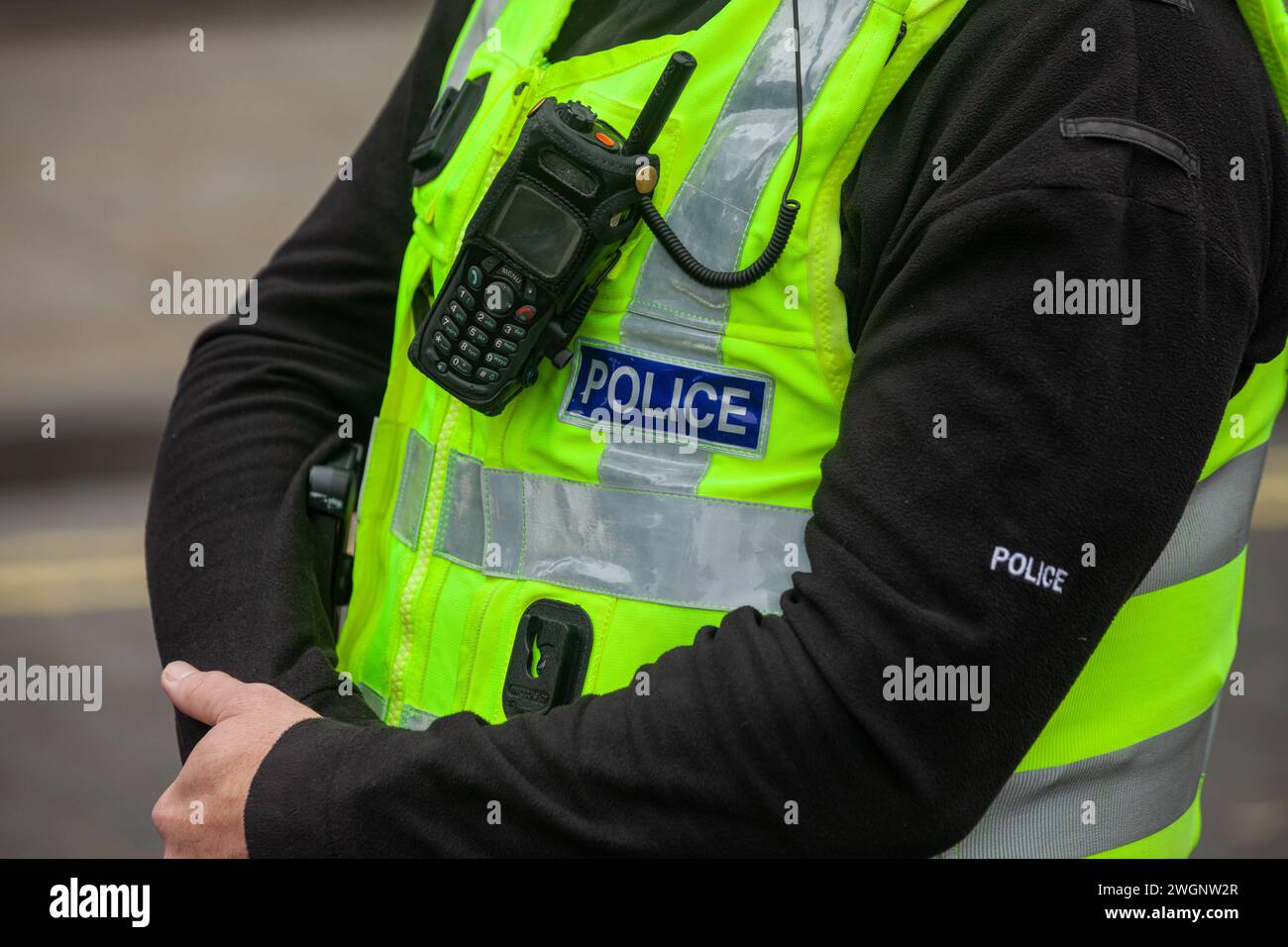 Un primo piano di un poliziotto che indossa un giubbotto alto e una radio Foto Stock