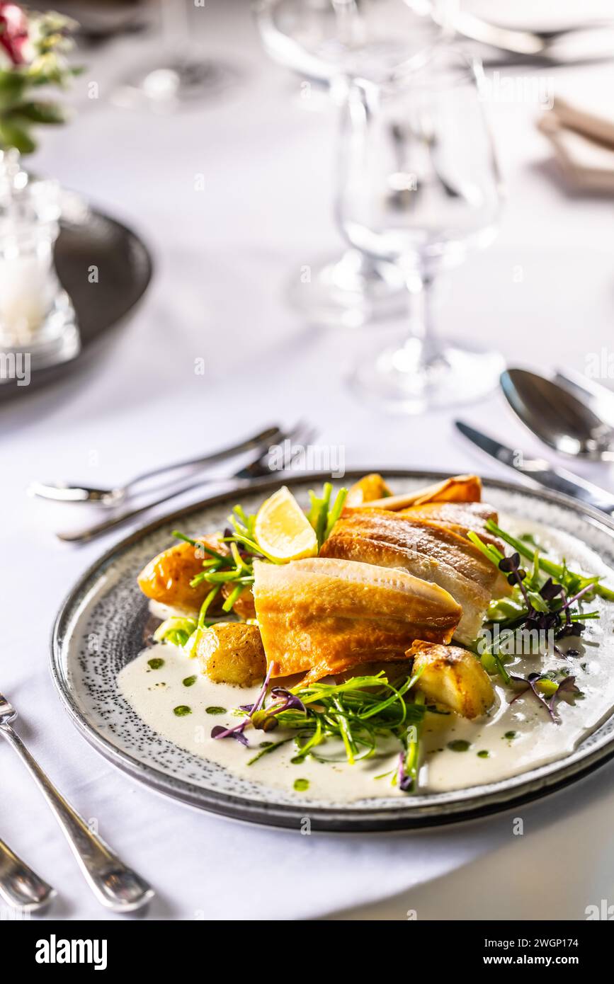 Filetto di trota leggermente affumicato, patate al forno, salsa di beurre blanc, salsa al porro e lime. Serve in modo creativo pesce su un piatto nel ristorante. Foto Stock