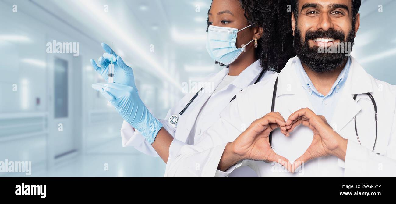 Un uomo e una donna medico professionale in camici da laboratorio, uno che prepara un vaccino con una siringa Foto Stock