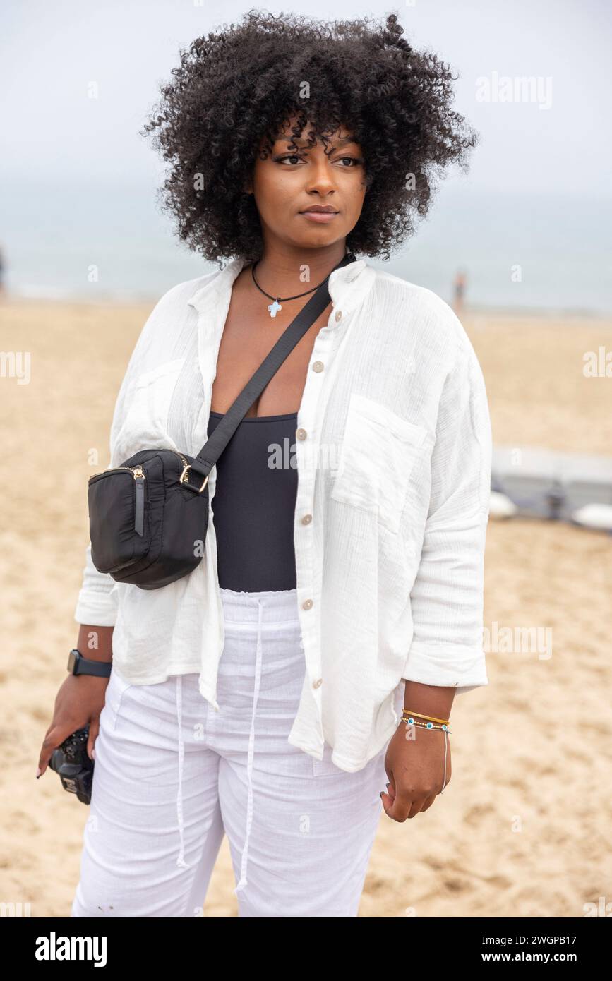 Un ritratto di una giovane donna nera sulla spiaggia, sta guardando fuori dalla macchina fotografica. Foto Stock