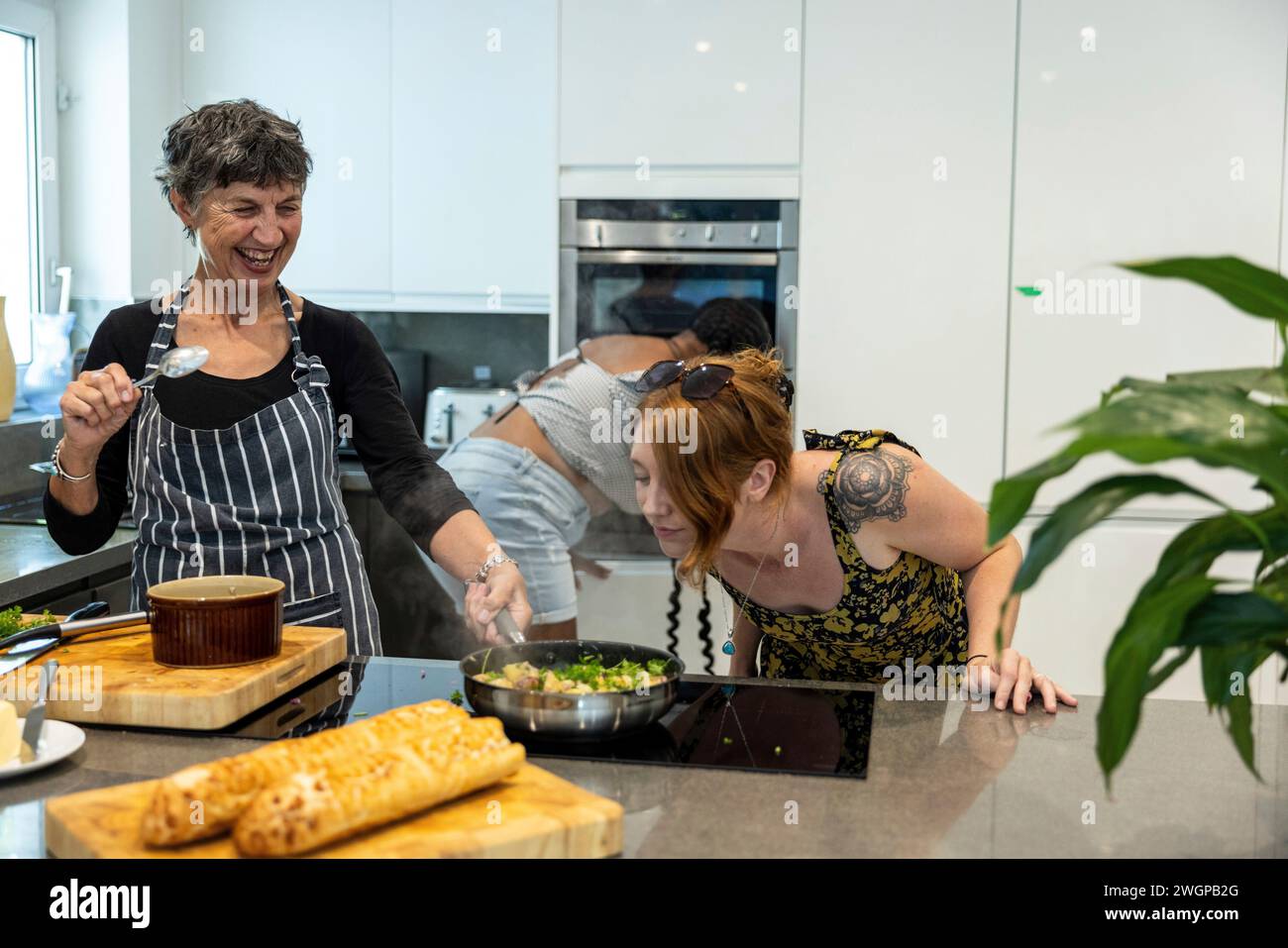 Un gruppo misto di amiche che preparano cibo da festa in una cucina moderna Foto Stock