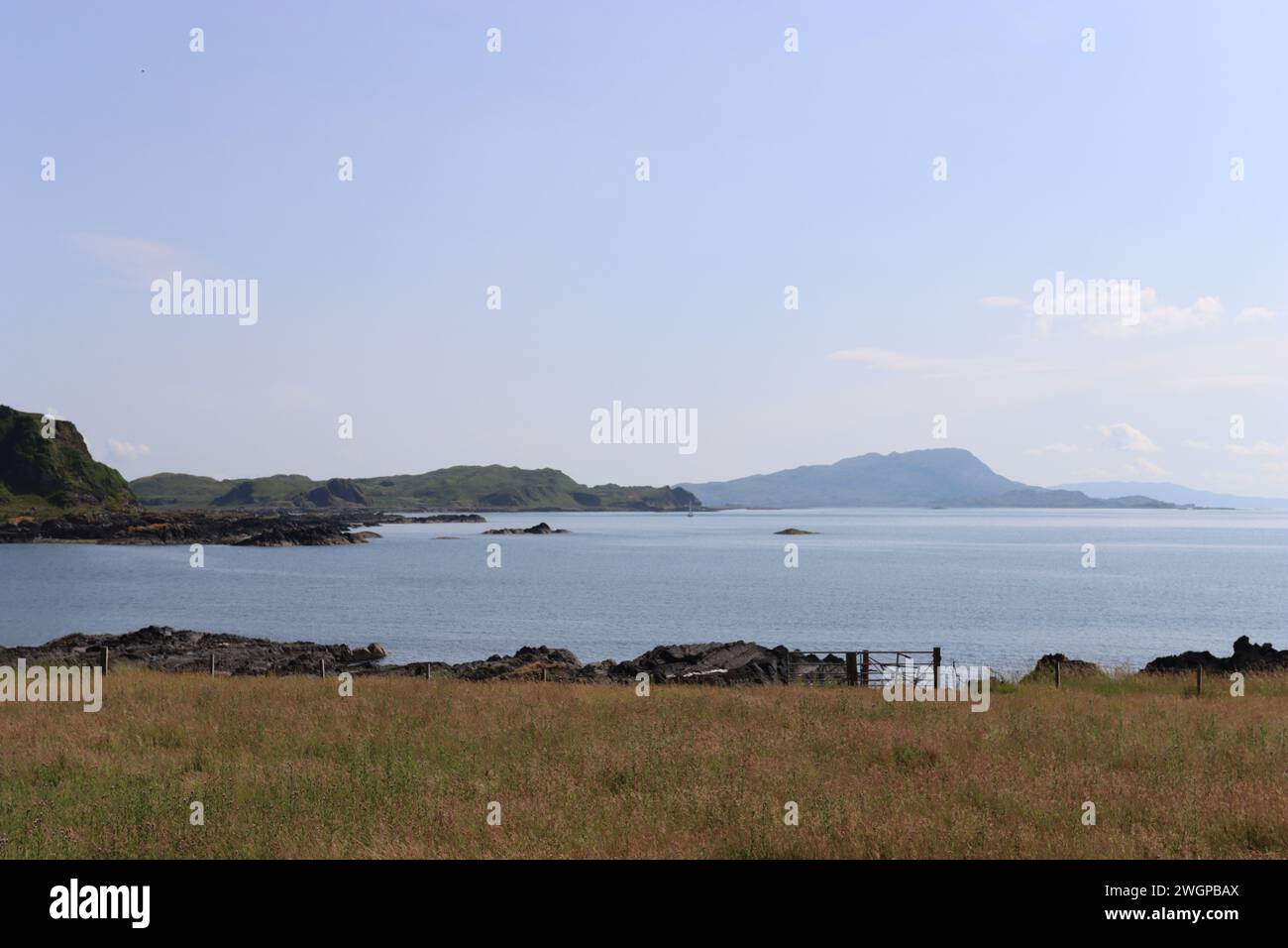 Ammira le remote isole scozzesi circondate dal mare blu calmo in una giornata di sole Foto Stock