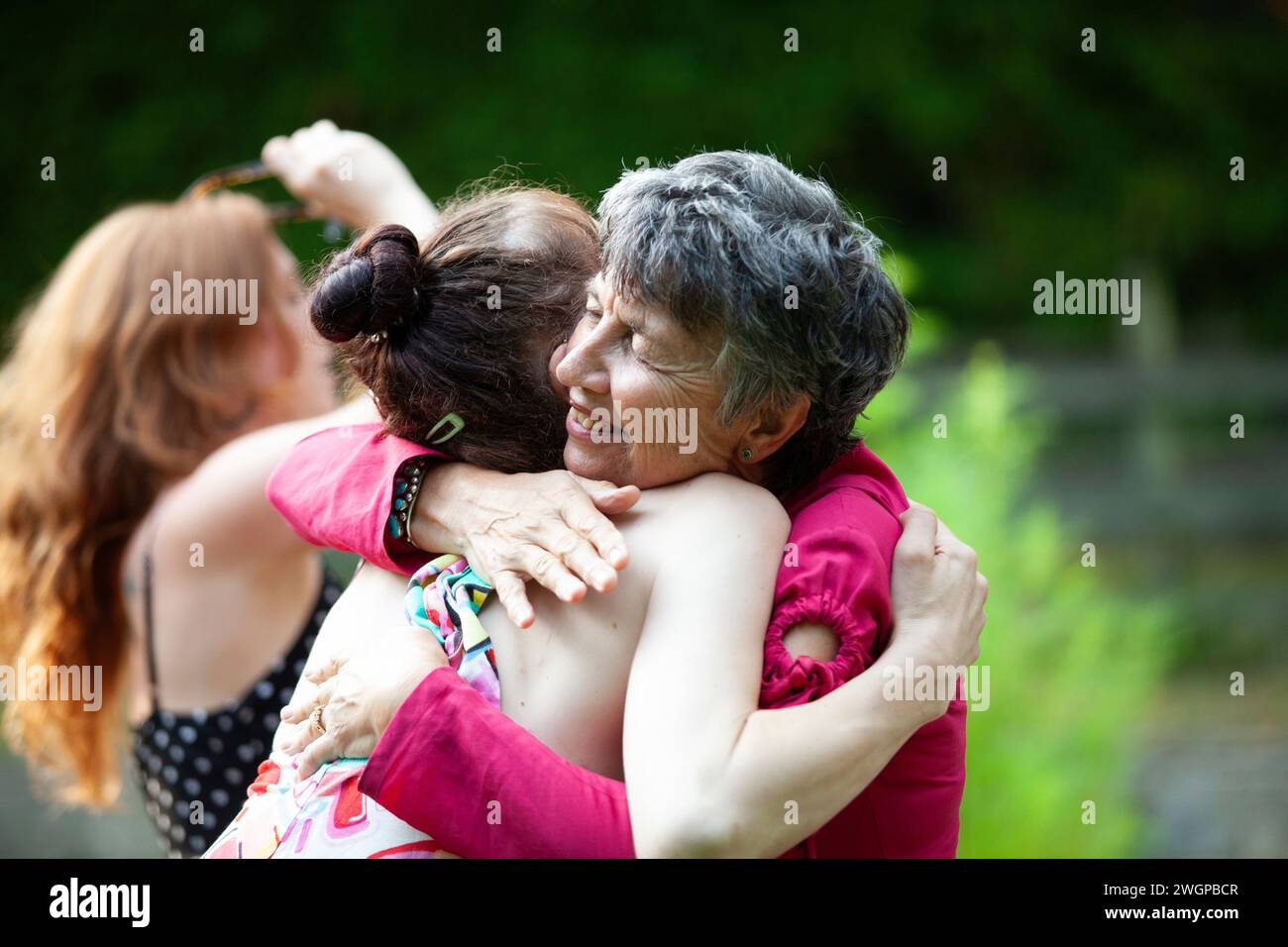 Una nonna abbraccia la sua nipote trans ad una festa estiva in giardino Foto Stock