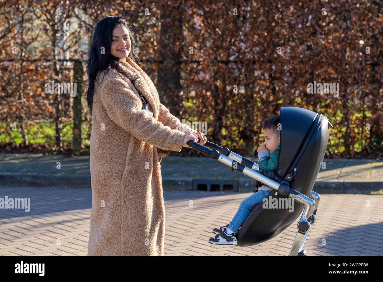Madre felice che porta il suo bambino a fare una passeggiata ai negozi Foto Stock