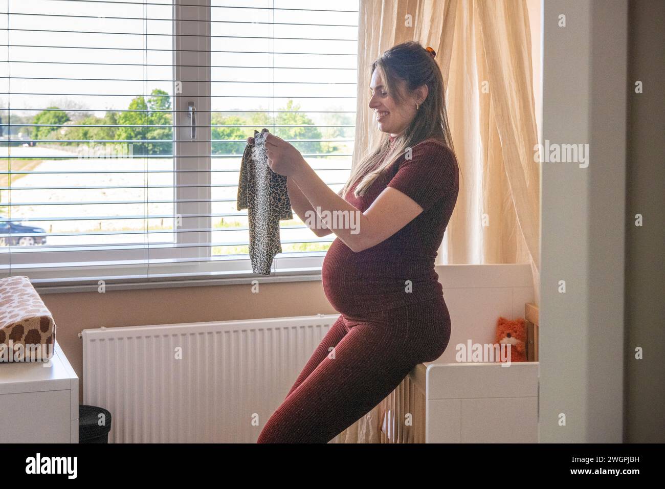 La madre incinta si prende una pausa mentre pulisce i vestiti Foto Stock