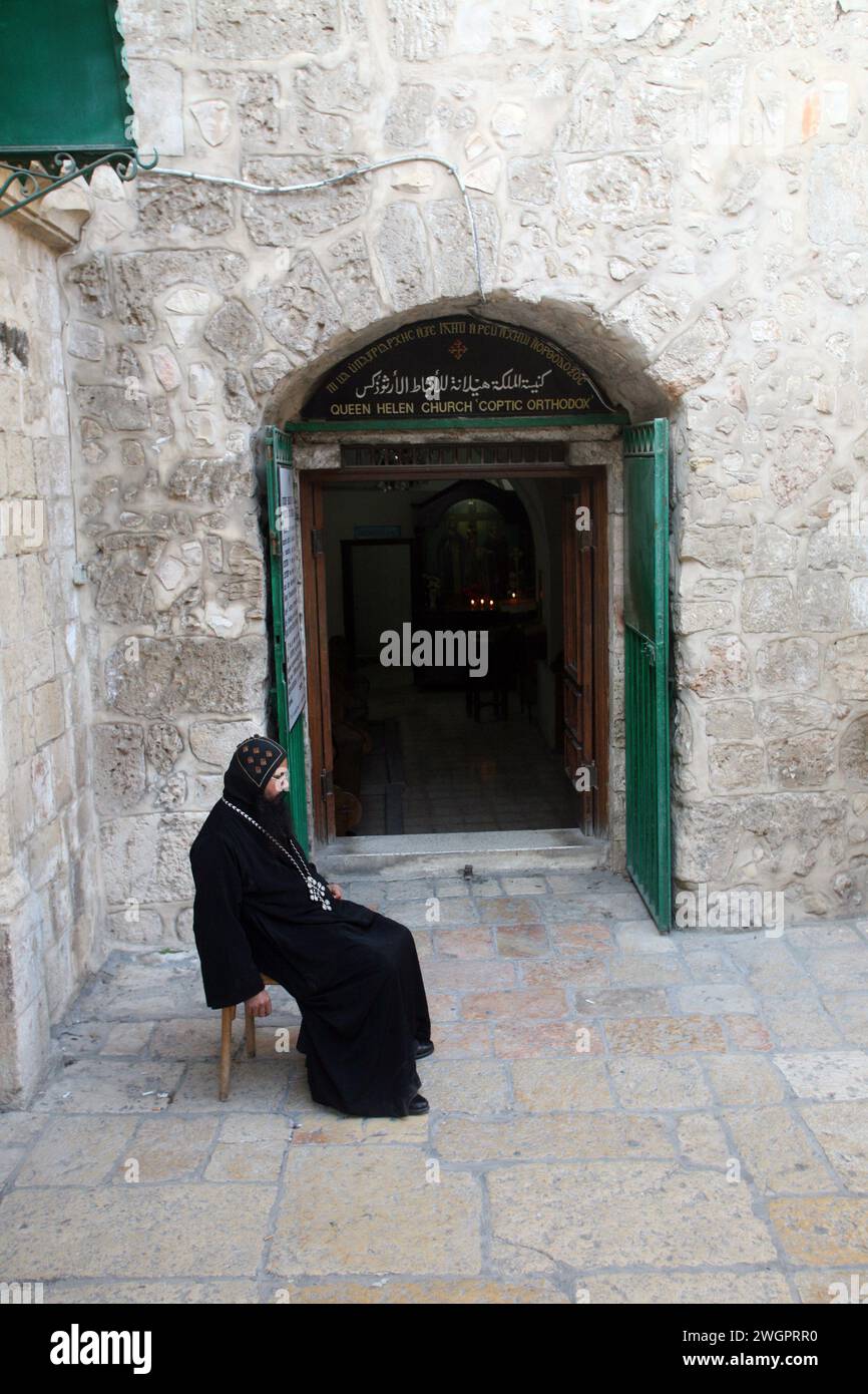 Cortile della Chiesa del Santo Sepolcro, monaco copto seduto davanti alla porta della Chiesa copta a Gerusalemme, Israele Foto Stock