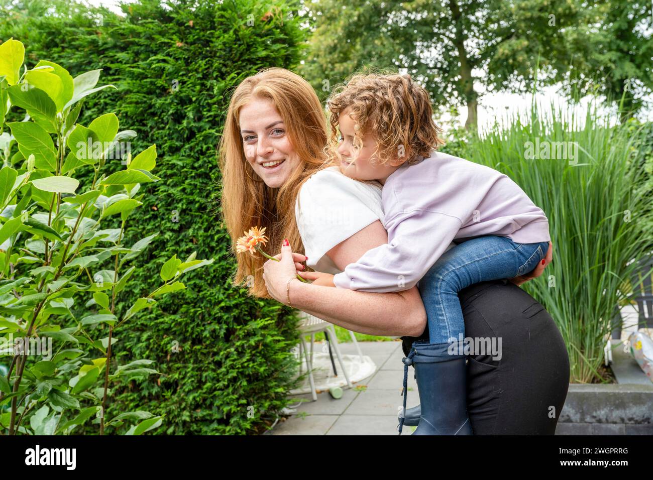 Madre e figlio che giocano in giardino con un maialino Foto Stock