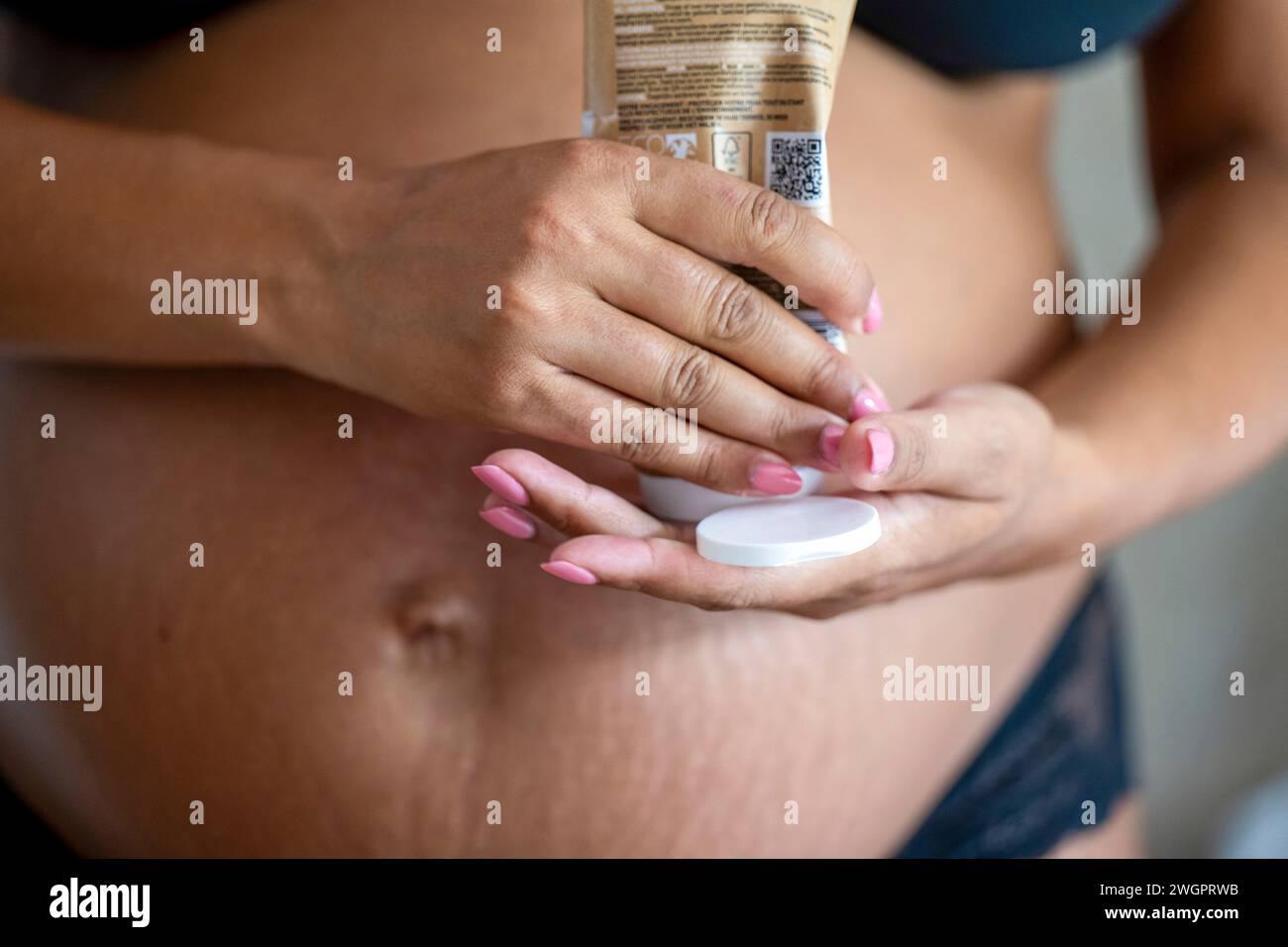Madre incinta che applica la crema al pancino Foto Stock