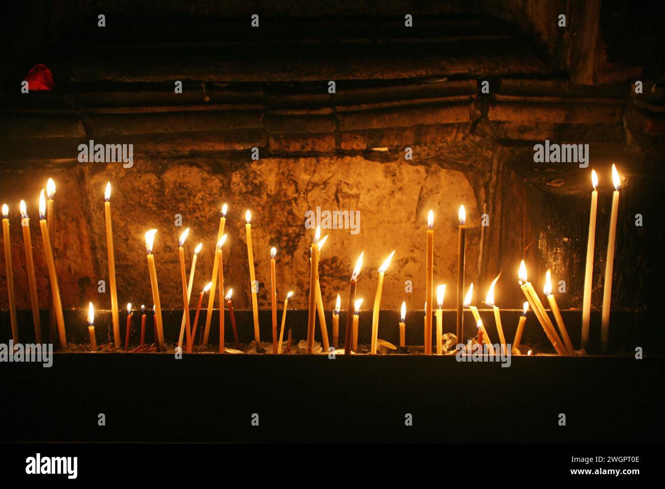 Pellegrini che bruciano una candela vicino al luogo in cui Gesù Cristo è stato crocifisso nella Chiesa del Santo sepolcro di Gerusalemme, Israele Foto Stock