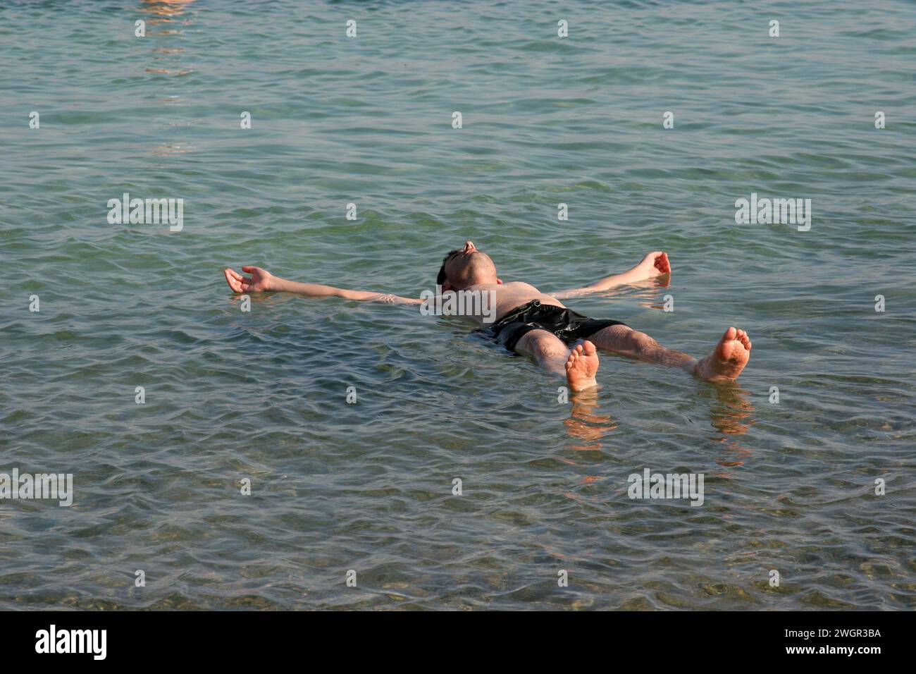 Bagnante galleggianti in super acque salate del Mar Morto in Israele Foto Stock