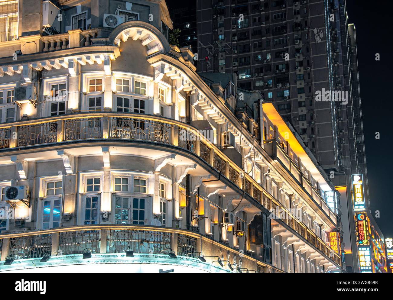 Un paesaggio urbano notturno con finestre illuminate e un edificio prominente sullo sfondo, che proietta riflessi accattivanti Foto Stock