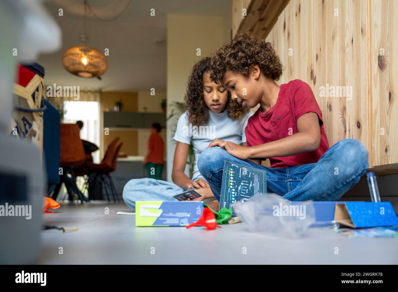 Fratello e sorella di razza mista che giocano contenti insieme felici sul pavimento con i giochi Foto Stock