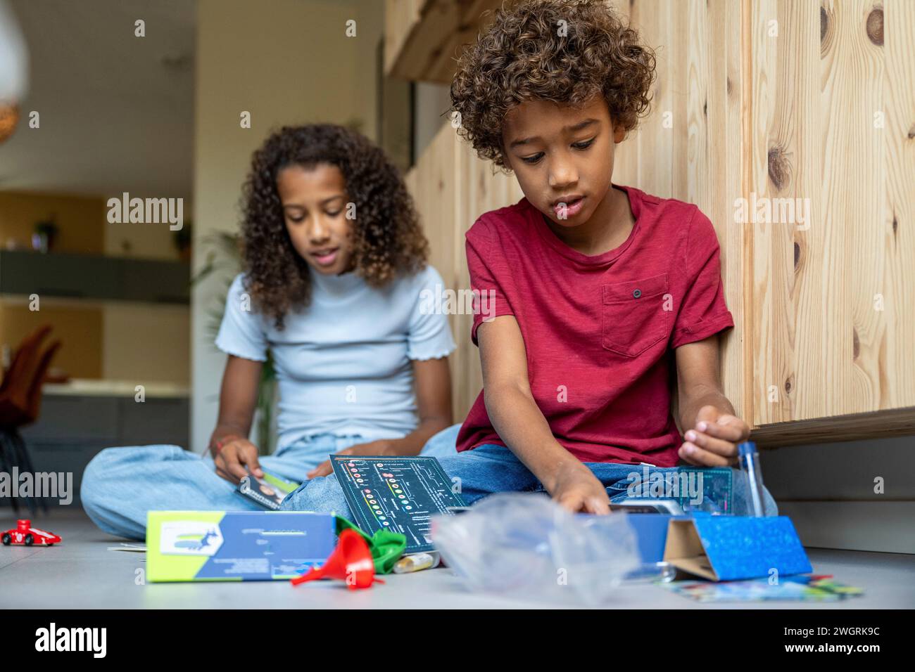 Fratello e sorella di razza mista che giocano contenti insieme felici sul pavimento con i giochi Foto Stock