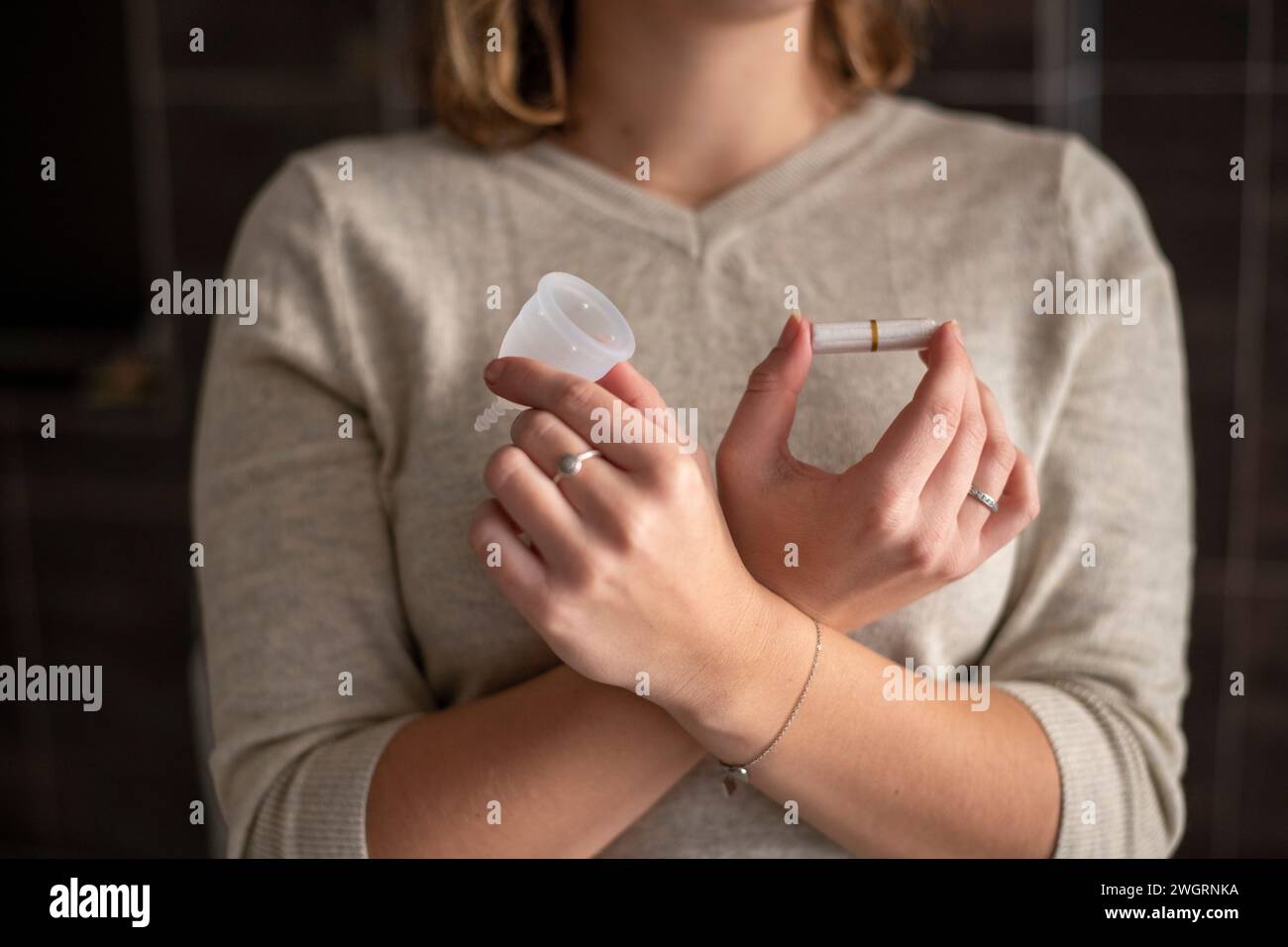 Donna che tiene i suoi prodotti mensili per la salute delle mestruazioni, tazza e tampone Foto Stock